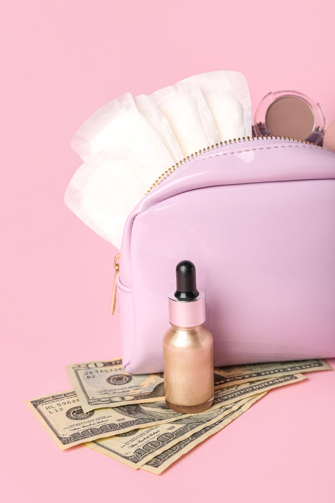 Lady's Cosmetic Bag with Menstrual Pads, Makeup Products and Money on Pink Background